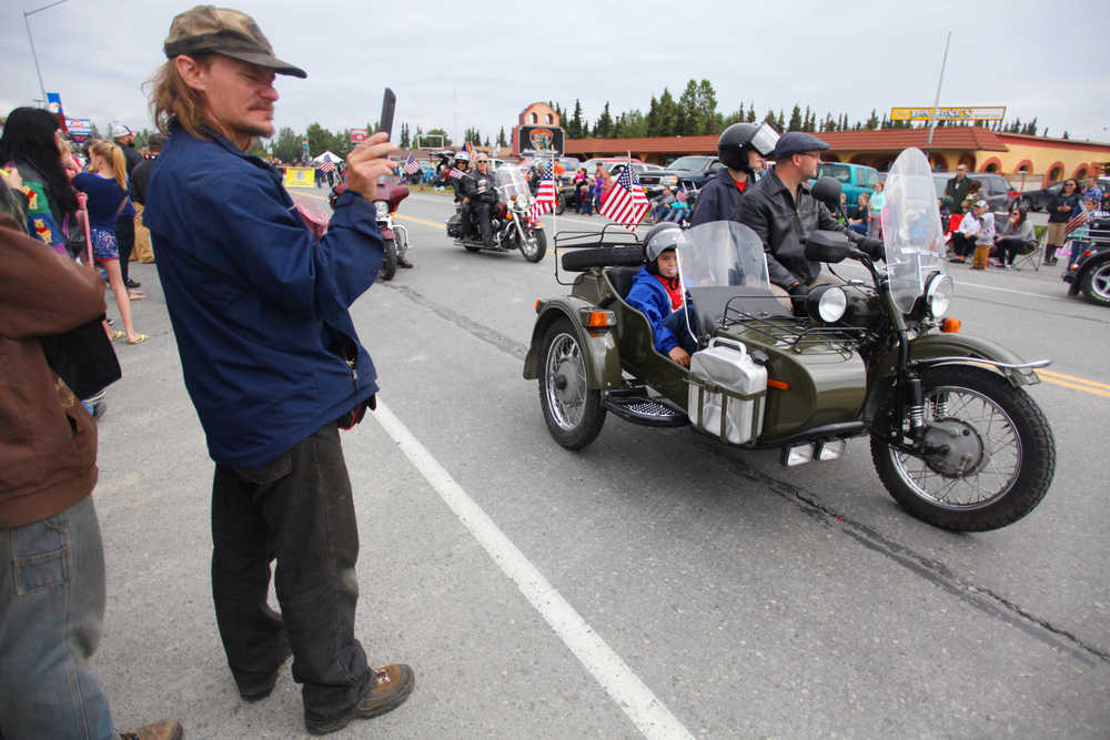 Photo by Kelly Sullivan/ Peninsula Clarion Alfred Port films the procession of antique cars in Kenai's Fourth of July Parade on Monday, July 4, 2016 in Kenai, Alaska.