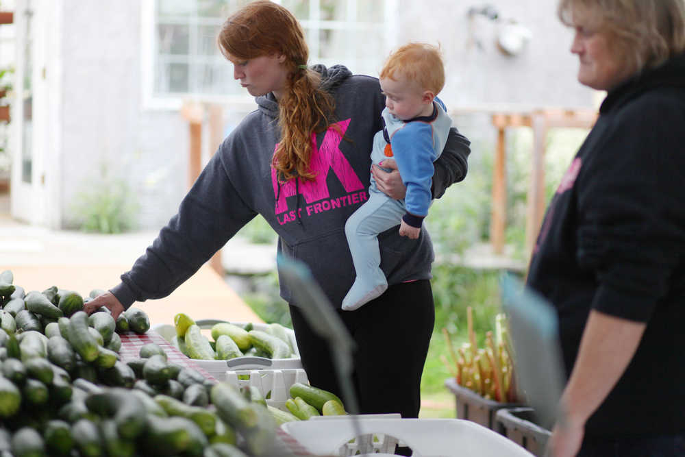 Photo by Kelly Sullivan/ Peninsula Clarion Bradley Whitaker helps mom Sarah Whitaker chose cucumbers during their Community Supported Agriculture subscription pickup Wednesday, July 6, 2016, at Ridgeway Farms in Soldotna, Alaska. This year 66 people signed up to purchase their local weekly produce hauls at the farm, and there is still room for others to buy a spot.