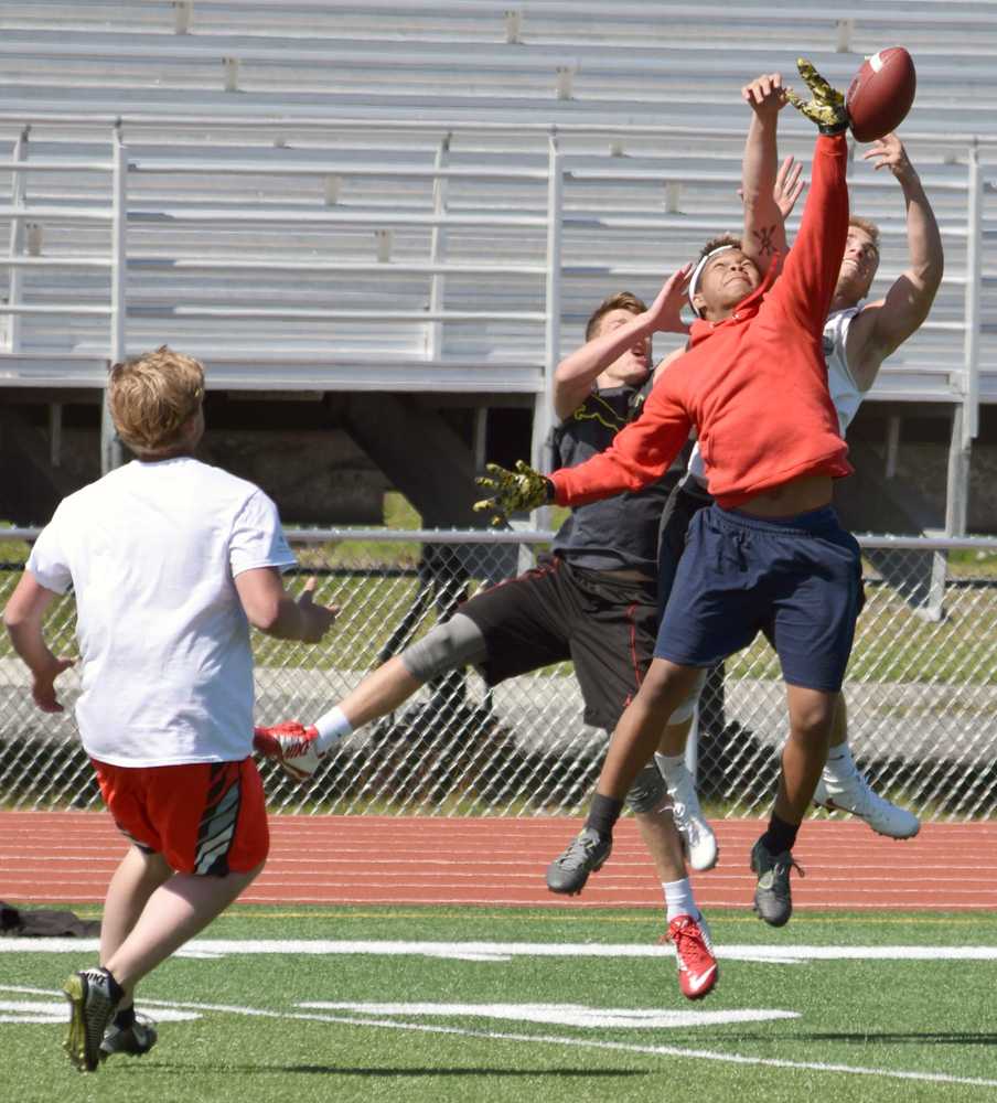 Photo by Jeff Helminiak/Peninsula Clarion Kenai Central's James Siamani goes up for the ball against Titus Riddall (back left) and Chase Gillies (back right) Friday during a passing drill at the Alaska All Star Football Camp at Kenai Central High School.
