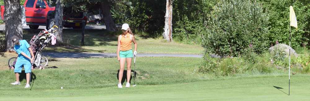 Photo by Jeff Helminiak/Peninsula Clarion Shane Sundberg of Sterling Elementary chips on to the 18th green as Anika Richards looks on Tuesday at the Birch Ridge Jr Masters at Birch Ridge Golf Course in Soldotna.