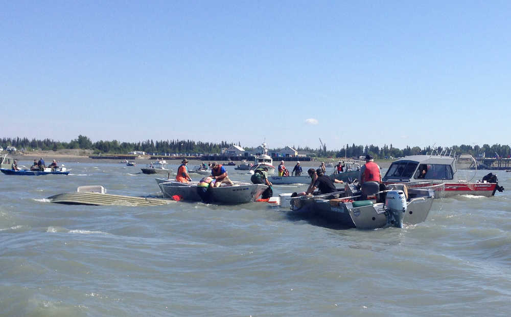 Photo by Megan Pacer/Peninsula Clarion Two bystanders watch over a small boat at the Kenai City Dock that capsized Tuesday, July 19, 2016 in Kenai, Alaska. Its four occupants were rescued quickly by other boaters, and others towed the vessel to shore.