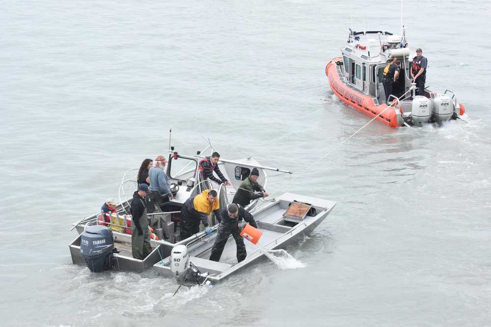 Photo by Megan Pacer/Peninsula Clarion Members of the Kenai Fire Department and Kenai Police Department tow two boats behind them - one that capsized and another that came to the rescue - while passengers work to bail out the capsized boat Friday, July 22, 2016 on the Kenai River in Kenai, Alaska. The three people in the capsized vessel were all saved from the water, and no one was harmed.