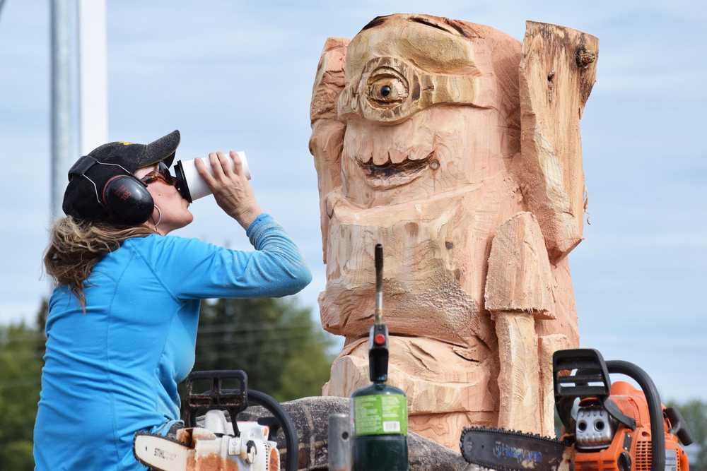 Photo by Megan Pacer/Peninsula Clarion Carmen West, of Hatchers Pass, takes a quick coffee break while carving up her masterpiece creation during this year's Sawfest Competition during Progress Days on Saturday, July 23, 2016 outside Stanley Chrysler in Soldotna, Alaska.