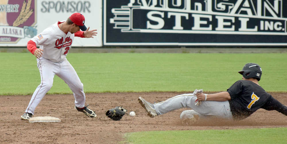 Photo by Jeff Helminiak/Peninsula Clarion Aaron Arruda of the Anchorage Bucs slides in safe after Oilers shortstop Trey Dawson lost his glove Sunday at Coral Seymour Memorial Park in Kenai.