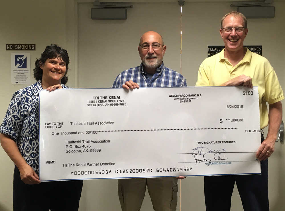 Tri the Kenai triathlon race director Tony Oliver, center, presents a donation of $1,000 raised during the triathlon in June to Tsalteshi Trails Association treasurer Lauri Lingafelt, left, and president John Pothast.