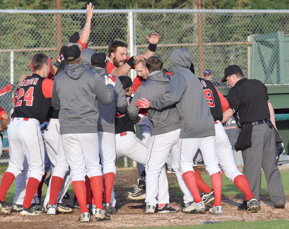 Photo by Jeff Helminiak/Peninsula Clarion Oilers third baseman Jeffrey Chapuran (center, hand on head) is mobbed by teammates after hitting a walk-off home run against the Chugiak Chinooks on Friday at Coral Seymour Memorial Park in Kenai.