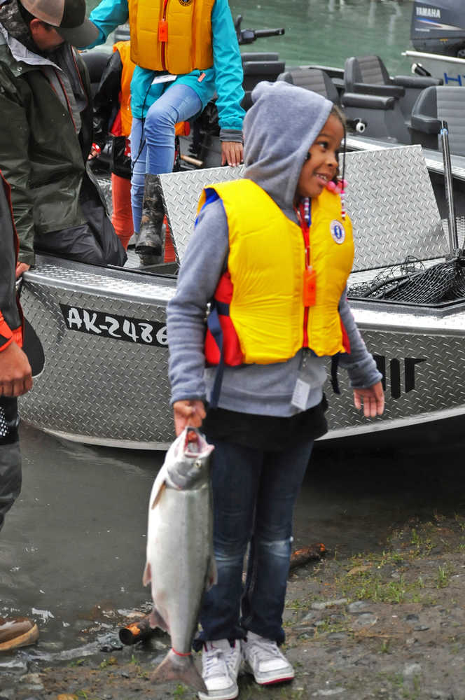 Photo by Elizabeth Earl/Peninsula Clarion Jezaniah Nelson, 8, of Anchorage, tries to get comfortable with holding her silver salmon through its gills at Centennial Campground's boat launch during the annual "Take Our Kids Fishing" event sponsored by the Boys & Girls Club and the Kenai River Foundation on Thursday, Aug. 11, 2016 in Soldotna, Alaska. The free event offers kids a chance to learn about the river and go out fishing with guides who volunteer their time.