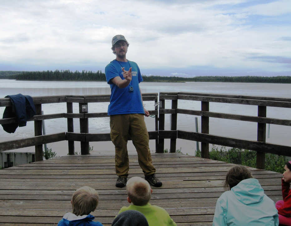 Brad Stoner,  in his fourth internship with the Student Conservation Association, describes a stickleback to fourth- and fifth-graders at Headquarters Lake as part of the Get out & Get Dirty summer camp at Kenai National Wildlife Refuge. (Photo courtesy Kenai National Wildlife Refuge)
