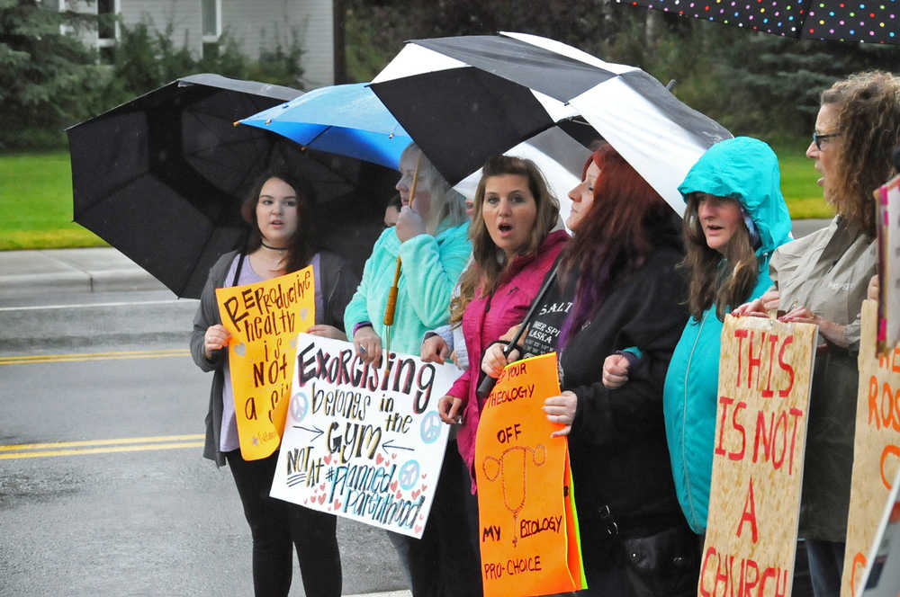 Photo by Elizabeth Earl/Peninsula Clarion Counter-protesters line up and chant "We are the wall, the separation of church and state" near where members of the Catholic Church gathered to pray near the Kenai Peninsula Borough Administration Building on Wednesday, Aug. 17, 2016 in Soldotna, Alaska. The church members decided to pray outside the borough administration building after a Satanic invocation was given to open the borough assembly meeting Aug. 9.