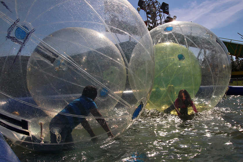 Photo by Ben Boettger/Peninsula Clarion Children, attempting to run on the low-friction surface of water, play in inflatable spheres floating on top a wading pool at the Kenai Peninsula Fair on Saturday, Aug 20, 2016 in Ninilchik, Alasaka. The bubble pool was one of several attractions in the amusment section of the fair, which also included bungee trampolines, a Tilt-a-whirl, swings, a slide and a Zipper ride.