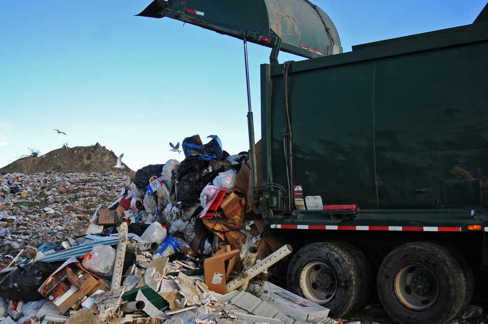 Photo by Elizabeth Earl/Peninsula Clarion Alaska Waste driver Will Bunch navigate's a dump truck's arms as he deposits the contents of a bin into the back of the truck on Thursday, July 21, 2016 in Kenai, Alaska.