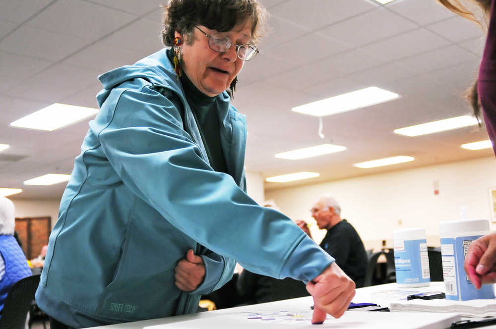 Photo by Elizabeth Earl/Peninsula Clarion Virginia Shook of Kenai makes a fingerprint on a painting the patients of Peninsula Radiation Oncology Center made at the center's second annual Patient Appreciation Luncheon on Thursday, Sept. 8, 2016 at Central Peninsula Hospital in Soldotna, Alaska. Shook, who said she is now cancer-free, said her own cancer surprised her during a routine checkup that she had thought about skipping. "It just totally didn't see it coming," she said. She encouraged everyone to always have regular screenings.