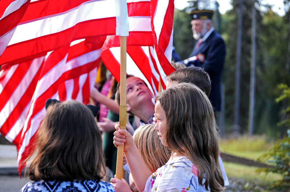 Photo by Elizabeth Earl/Peninsula Clarion Maggie Grenier, a student at Nikiski North Star Elementary School, holds a flag during a flag dedication ceremony Friday, Sept. 9, 2016 at the Nikiski Senior Center in Nikiski, Alaska. The senior center staff and community members raised money themselves for the flag poles over the course of about six weeks earlier this summer, said Jill Smith, the senior center's executive director.