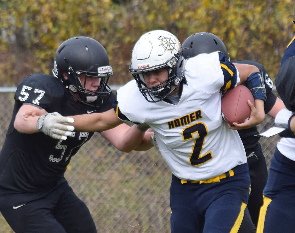 Photo by Joey Klecka/Peninsula Clarion Homer quarterback Jaime Rios (2) stiff arms Nikiski lineman Tyler Litke Saturday at Nikiski High School.