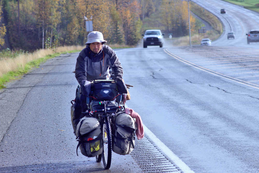 Ben Boettger/Peninsula Clarion Hiromu Jimbo bicycles up the Sterling Highway from Mackey Lake Road, laden with camping and cooking gear, on Wednesday, Sept. 21 outside of Soldotna. The Japanese long-distance cyclist has been riding around the world since 2009 and is presently on his way to Homer. Afterward he plans to ride back up through the central peninsula to Whittier, take a ferry to Valdez, and ride into Canada's Yukon Territory, where he will spend the winter in a village.