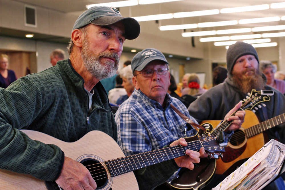 Ben Boettger/Peninsula Clarion Guitarist Myke Ables (left), mandolinist Rick Epling, and guitarist Nathan Epling look toward the song leader of their bluegrass jam at the Kenai Fall Fest, Thursday Sept. 22 at the Kenai Senior Center. In addition to being part of the festival, the event was one of the Senior Center's weekly Thursday night jam sessions.  A microphone stand on wheels rolled around the circle of about 10 musicians, who took turns calling a tune and a key. "Musically, this is all about having fun," Rick Epling said. "If it goes much beyond that, it sort of defeats the point."