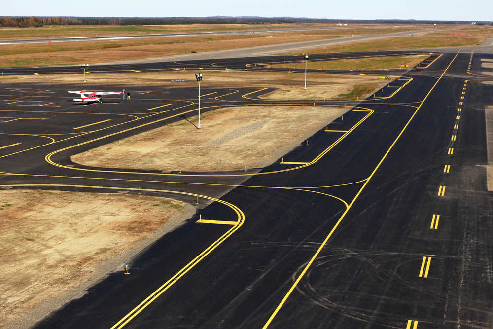 Photo by Ben Boettger/Peninsula Clarion Fresh asphalt paving on the taxiways and tie-down area of the Kenai Municipal Airport sits ready for use Thursday, Sept. 29, 2016 in Kenai, Alaska. The airport's recently finished taxiway rehabilitation replaced pavement from the 1980s that was buckled from frost heave and sat on a foundation of logs and debris laid during the airport's founding as a World War II-era military airbase. The renovation also improved the lights - the lightpoles surrounding the tie-down lot on the left are shorter and more directional LED lights, while the pavement-embedded marker lights on the right side of the taxiway are less exposed than the older post-mounted lights on the left.