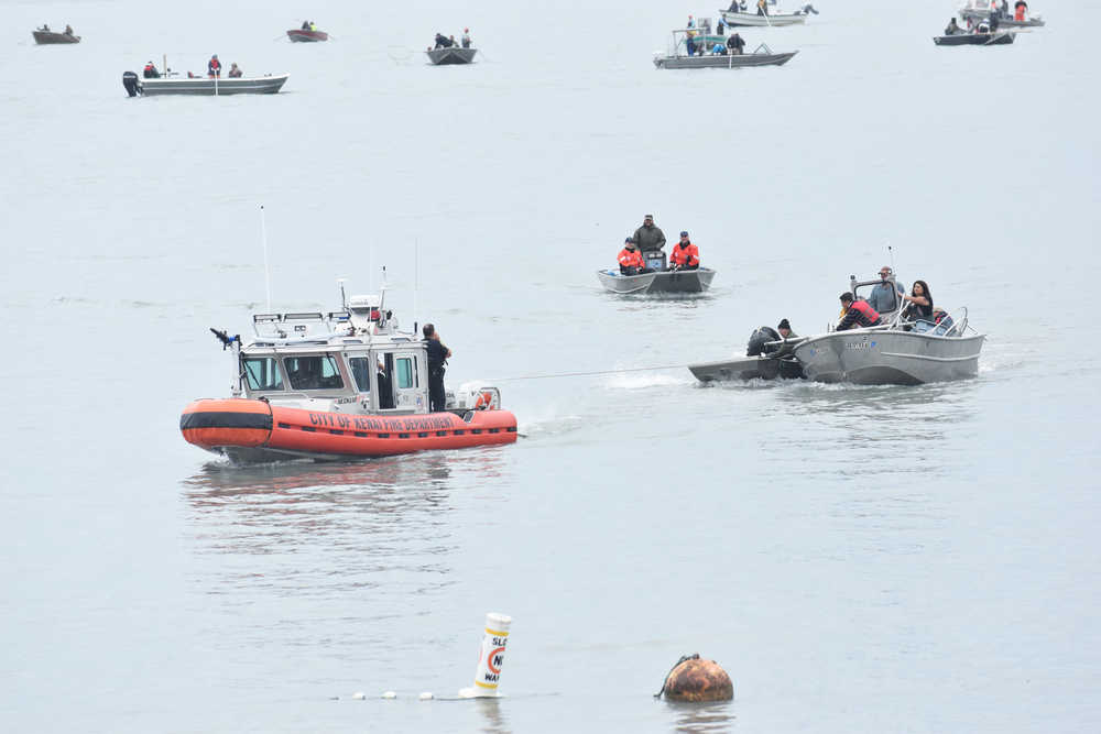 Photo by Megan Pacer/Peninsula Clarion In this July 22, 2016 photo, members of the Kenai Fire Department and Kenai Police Department tow two boats behind them - one that capsized and another that came to the rescue - while passengers work to bail out the capsized boat on the Kenai River in Kenai, Alaska. The three people in the capsized vessel were all saved from the water, and no one was harmed.