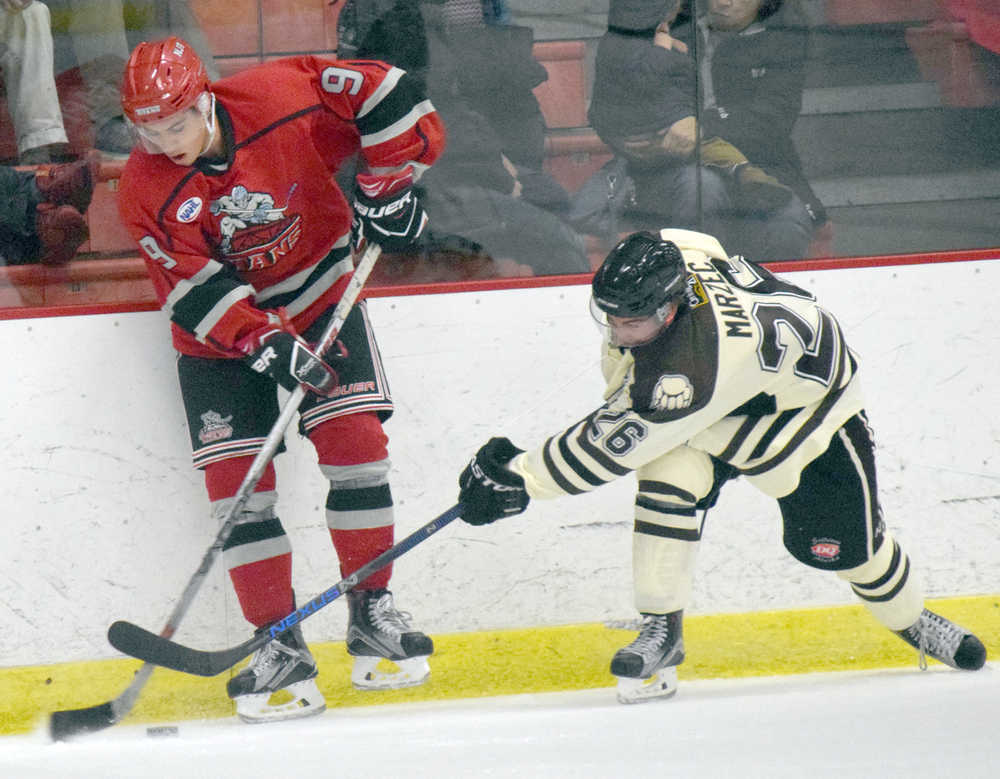 Photo by Jeff Helminiak/Peninsula Clarion New Jersey Titans forward Jordan Kaplan protects the puck from Brown Bears forward Jonathan Marzec on Friday at the Soldotna Regional Sports Complex.