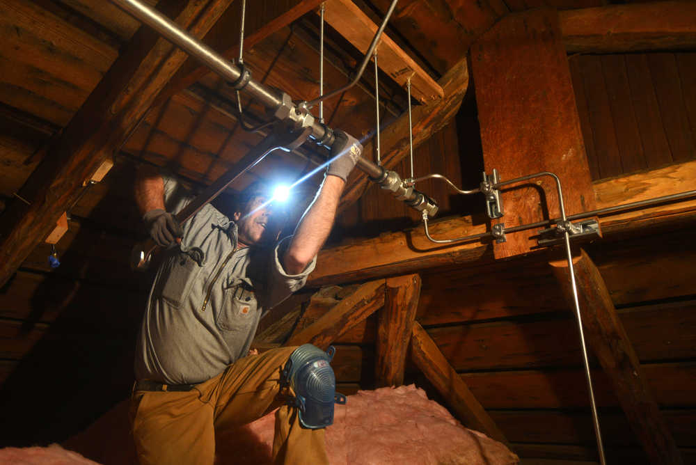 Photo by Ben Boettger/Peninsula Clarion Electrician Richard Cutting of Anchorage's Megawatt Electric tightens a fitting on a 38 millimeter main distribution pipe, part of the Holy Assumption of the Virgin Mary Russian Orthodox Church's new fire supression system, above the church's sanctuary Thursday, Oct. 6, 2016 in Kenai, Alaska.