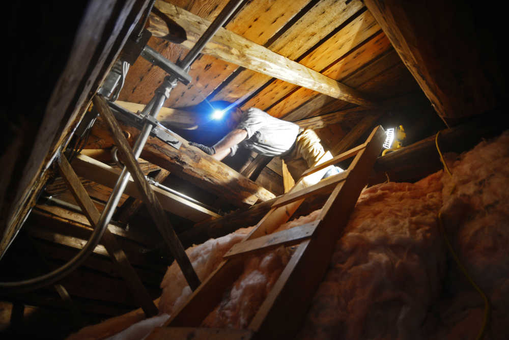 Ben Boettger/Peninsula Clarion Electrician Richard Cutter crawls through the roof space of Kenai's Holy Assumption of the Virgin Mary Russian Orthodox Church while installing a new fire supression system on Thursday, Oct. 6 in Kenai.