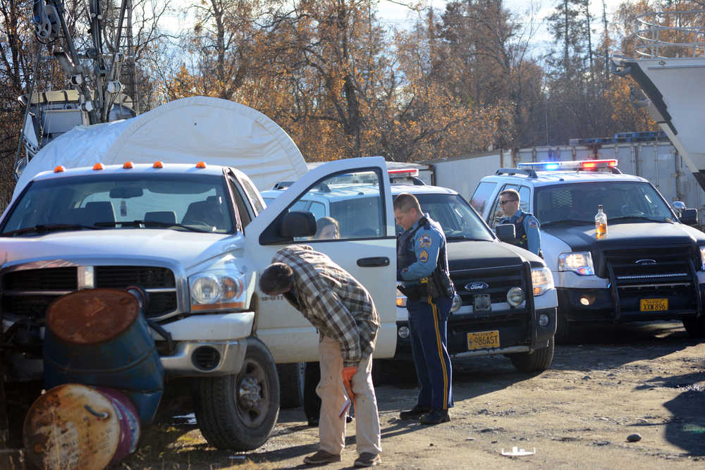 Alaska State Trooper Sgt. Dan Cox, center, examines a crashed truck at Northern Enterprises Boat Yard on Thursday afternoon. Paul Suter, 30, is accused of stealing the truck and evading troopers and Homer Police in a high-speed chase from Anchor Point to Homer. Police caught Suter after he crashed the truck. Troopers said Suter ran from the truck holding a gallon jug of Scotch whisky, seen here on the hood of a trooper vehicle. He's also charged with two counts of driving under the influence.