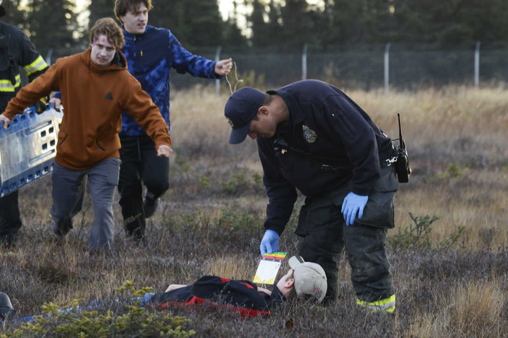 Photo by Megan Pacer/Peninsula Clarion Kenai River Brown Bears hockey player Bailey Seagraves poses as a dead plane crash victim and waits to be rescued during a mass casualty drill Tuesday, Oct. 11, 2016 at the Kenai Municipal Airport in Kenai, Alaska. The airport is required by the Federal Aviation Administration to hold the drill every three years to test its emergency planning.