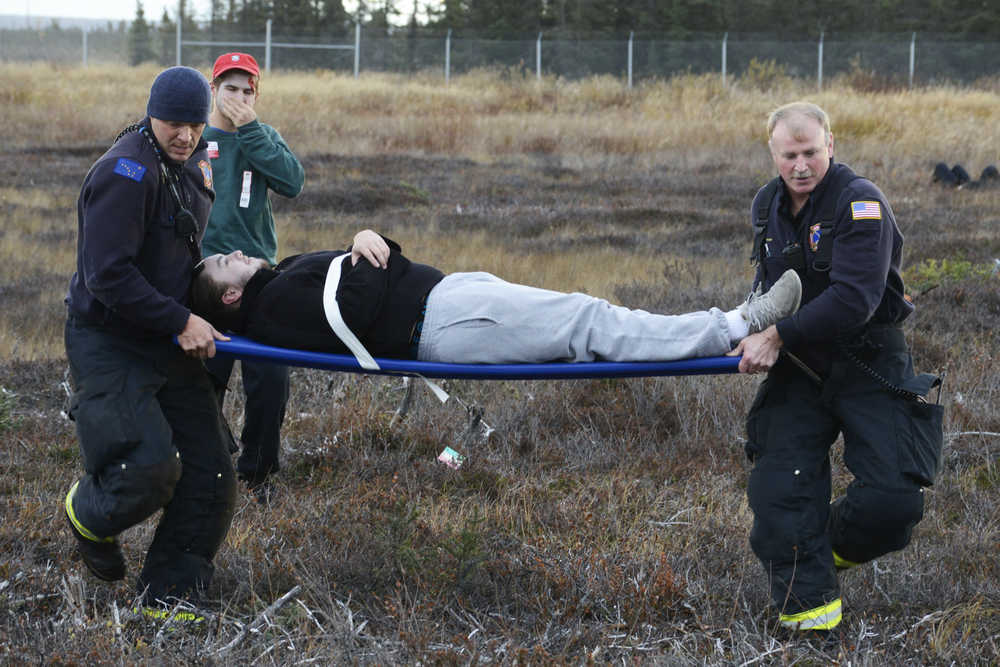 Photo by Megan Pacer/Peninsula Clarion Kenai Fire Battalion Chief Tony Prior and a Kenai firefighter carry a volunteer pretending to be an injured plane crash victim to safety on a stretcher during a mass casualty drill Tuesday, Oct. 11, 2016 at the Kenai Municipal Airport in Kenai, Alaska. The airport is required by the Federal Aviation Administration to hold the drill every three years to test its emergency planning.