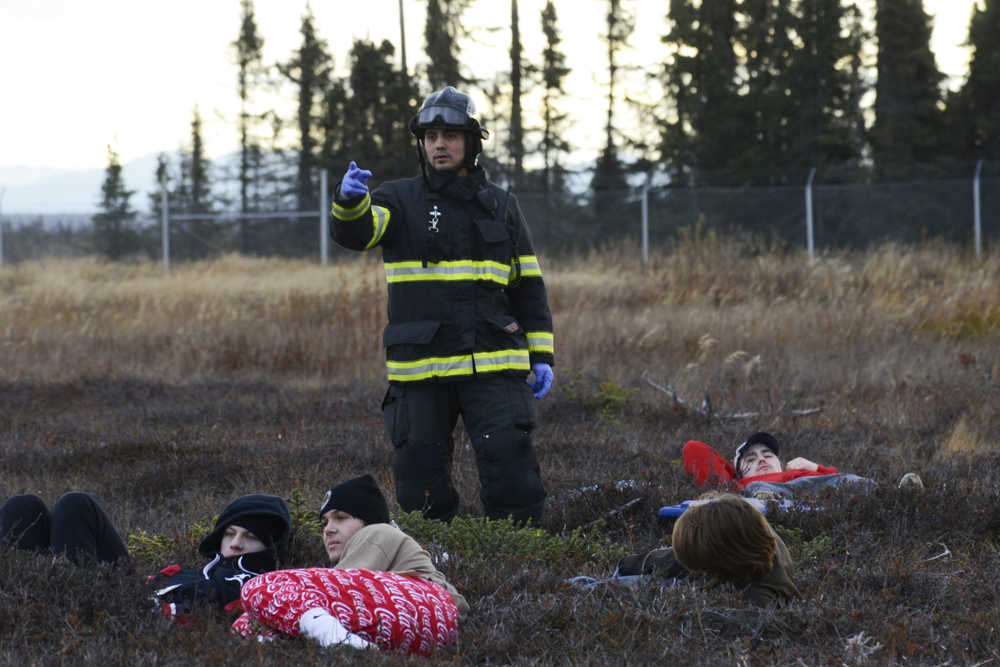 Photo by Megan Pacer/Peninsula Clarion A firefighter communicates with other emergency responders while volunteers wait to be rescued during a mass casualty drill Tuesday, Oct. 11, 2016 at the Kenai Municipal Airport in Kenai, Alaska. More than 30 volunteers turned out to act as plane crash victims and medics at the drill the airport is required by the Federal Aviation Administration to hold every three years to test its emergency planning.