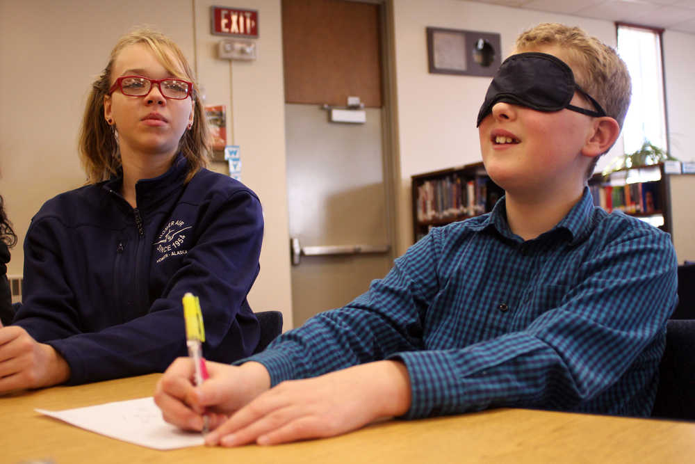 Ben Boettger/Peninsula Clarion Jessica Croom (left) serves as a sighted helper to blindfolded Tristan Arnold, making a drawing during River City Academy's Blindness Challenge on Thursday, Oct. 13 in Soldotna. After trying to draw and write on regular paper, the blindfolded students  used swell paper, which absorbs ink and expands, creating raised lines that a blind artist can feel.