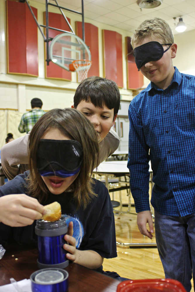 Ben Boettger/Peninsula Clarion Blindfolded Kaegan Koski eats lunch in the River City Academy cafeteria/gym, while fellow students Aiden Huff and blindfolded Tristan Arnold stand behind him on Thursday, Oct. 13 in Soldotna.
