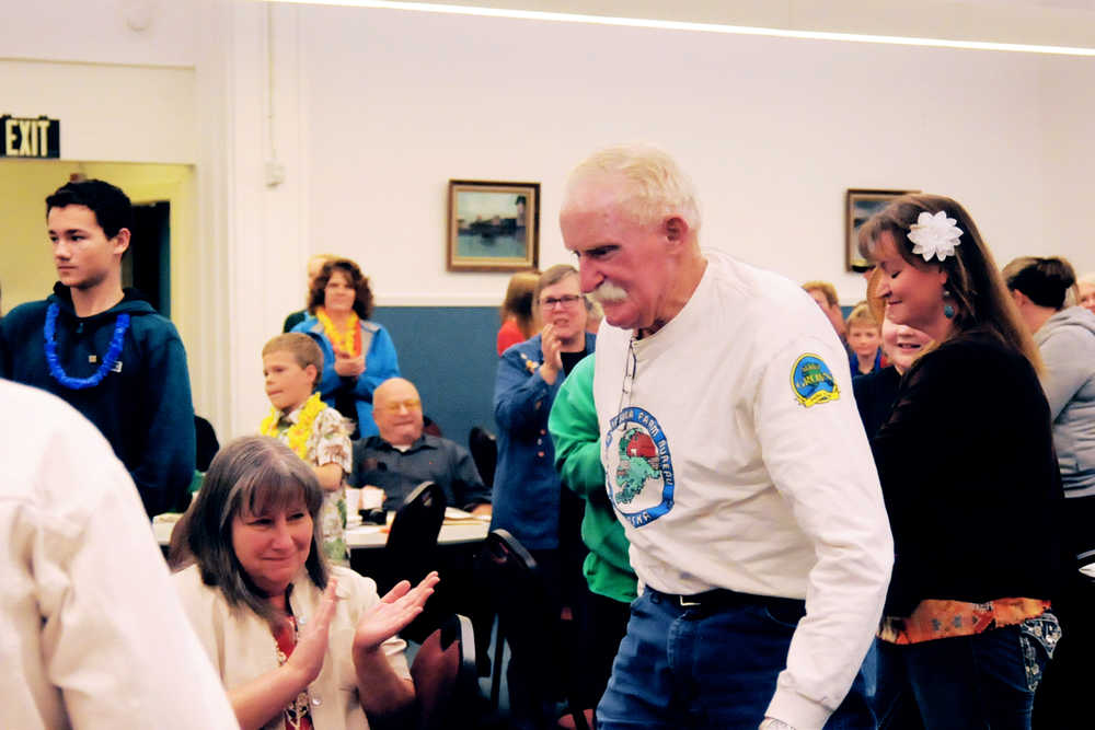 Photo by Elizabeth Earl/Peninsula Clarion Dr. Jerry Nybakken, a local veterinarian, walks up amid applause to receive a commendation from the participants in the local 4-H Club's Junior Market Livestock program Friday, Oct. 14, 2016 in Nikiski, Alaska. Nybakken, who regularly makes home visits to care for farm animals, helps out with the efforts to get the market livestock that the kids raise to the fair in Ninilchik each year. At the annual 4-H awards banquet, the participants presented him with a signed photo and board thanking him for his work.