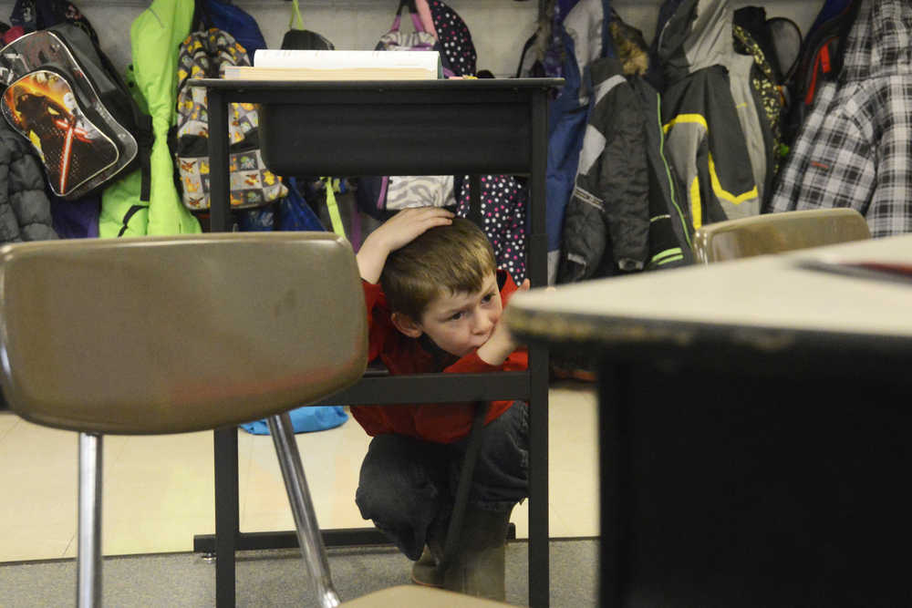 Photo by Megan Pacer/Peninsula Clarion Mountain View Elementary second grader Blake Kinsley, 7, crouches under his desk with his head covered during this year's Great Alaska ShakeOut earthquake drill Thursday, Oct. 20, 2016 at the school in Kenai, Alaska.