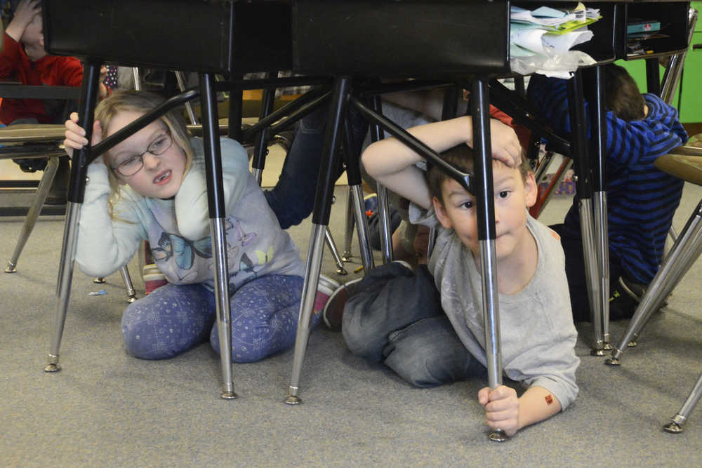 Photo by Megan Pacer/Peninsula Clarion Mountain View Elementary second graders Elsa Meyer, 7, and Devin Seaton, 7, wait under their desks with their head and necks covered during this year's Great Alaska ShakeOut earthquake drill Thursday, Oct. 20, 2016 at the school in Kenai, Alaska.
