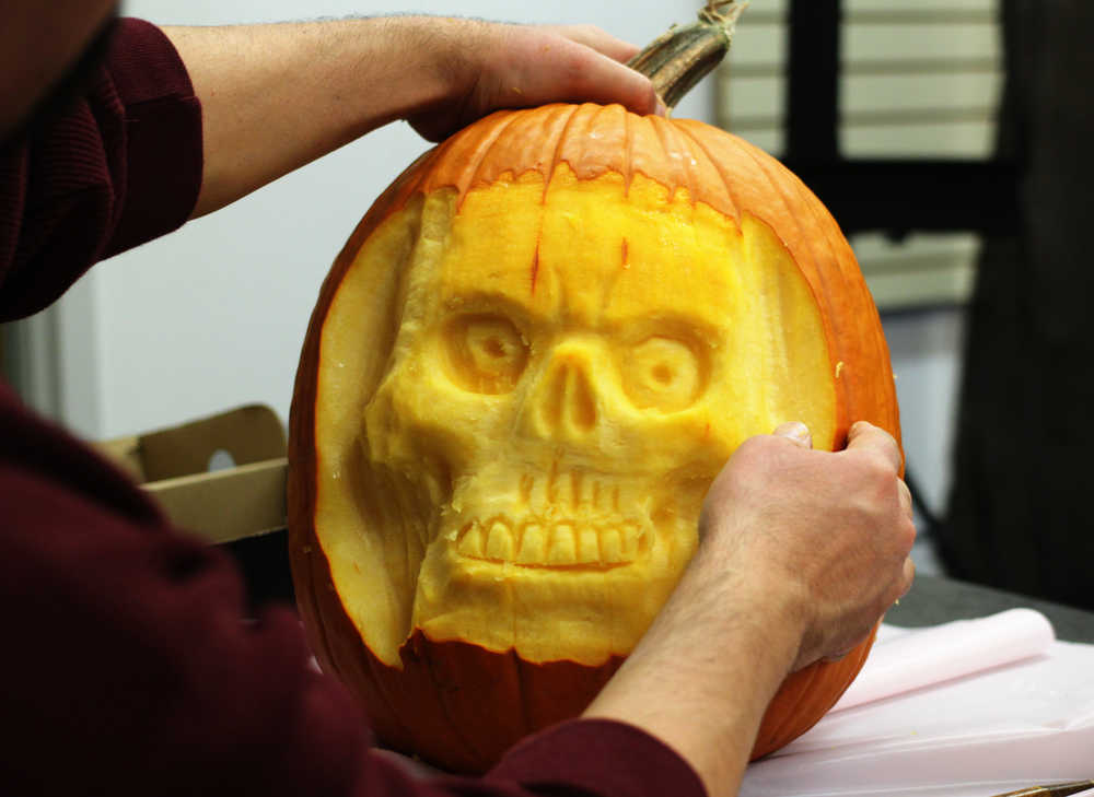 Photo by Ben Boettger/Peninsula Clarion Kenai Community Library children's librarian James Adcox examines a skull he's carved out of a pumpkin during a pumpkin-carving session on Tuesday Oct. 25 at the library in Kenai.