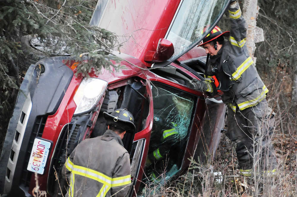 Photo by Elizabeth Earl/Peninsula Clarion Central Emergency Services first responders retrieve belongings from the inside of an overturned vehicle on Carver Drive near the intersection of Gene Street on Wednesday, Oct. 26, 2016 near Kenai, Alaska. Alaska State Troopers and CES responded to a report of a single-vehicle rollover around 5 p.m. Wednesday. The car's seven occupants got out safely, though CES transported one to Central Peninsula Hospital as a precautionary measure.