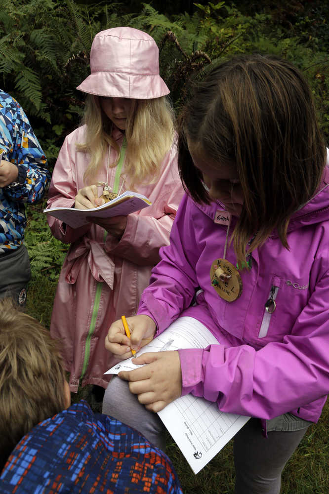 In this Oct. 6, 2016 photo, Outdoor School students Maya Herring, left, and Evie Larson enter notes in their field study notebooks during a lesson at Camp Howard in Mount Hood National Forest near Corbett, Ore. The outdoor education is unique to Oregon and is a rite-of-passage for public school students that's meant to instill a respect for nature in each generation - studies show it improves attendance and boosts test scores. (AP Photo/Don Ryan)