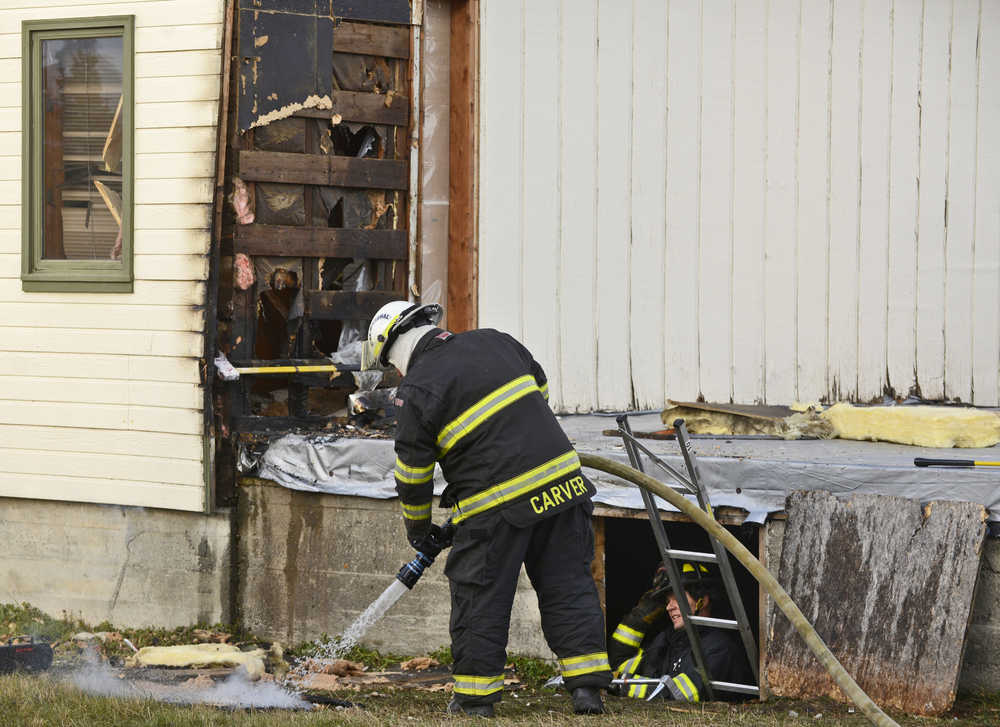 Ben Boettger/Peninsula Clarion Kenai Fire Marshal Tommy Carver sprays off smoldering material taken from the wall of the Cowan, Gerry, and Aaronson law office on Monday, Oct. 31 in Old Town Kenai. A patient leaving the nearby Cook Inlet Dental office called the Kenai Fire Department after seeing smoke from the building, and two Kenai fire engines responded at 2:11 pm. Kenai Fire Chief Jeff Tucker said the damage was confined to the corner wall and the two people inside the building weren't hurt.