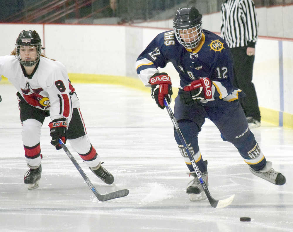Photo by Joey Klecka/Peninsula Clarion Homer forward Dimitry Kuzmin (12) carries the puck up the ice with Kenai Central defenseman Alyssa Stanton in tow Thursday evening at the Soldotna Regional Sports Complex.