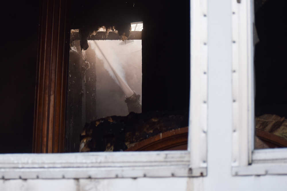Photo by Megan Pacer/Peninsula Clarion A firefighter sprays foam onto the damaged areas of a mobile home that caught fire Tuesday, Nov. 22, 2016 on Blanch Street, off of Kalifornsky Beach Road, near Soldotna, Alaska. Firefighters were able to put out the blaze in the back bedroom and bathroom area of the mobile home within minutes and none of the occupants were hurt.