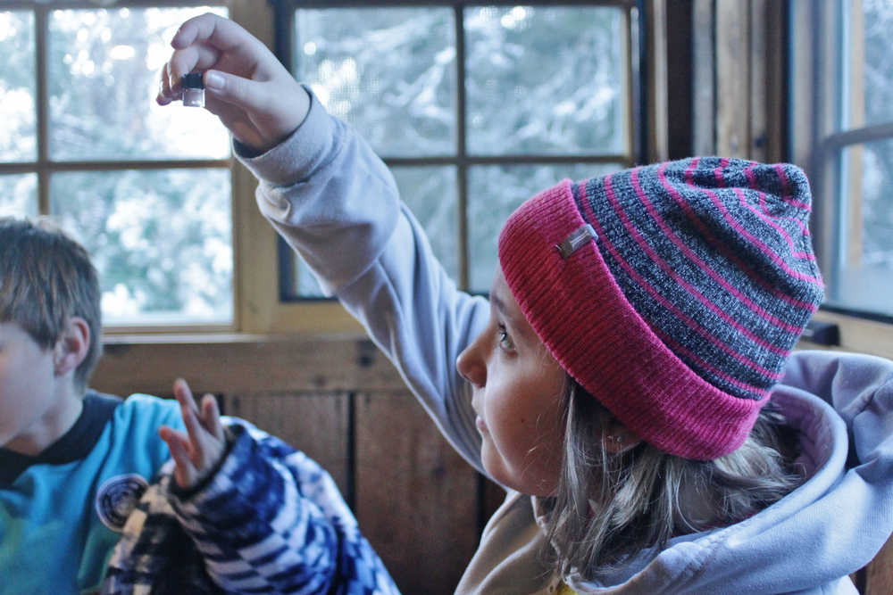 Ben Boettger/Peninsula Clarion Seward Elementary student Ayden Lapinskas holds a water-filled vial to the light to inspect the gold flakes she panned during a field trip to Manitoba cabin on Tuesday, Nov. 15 near the Seward Highway.