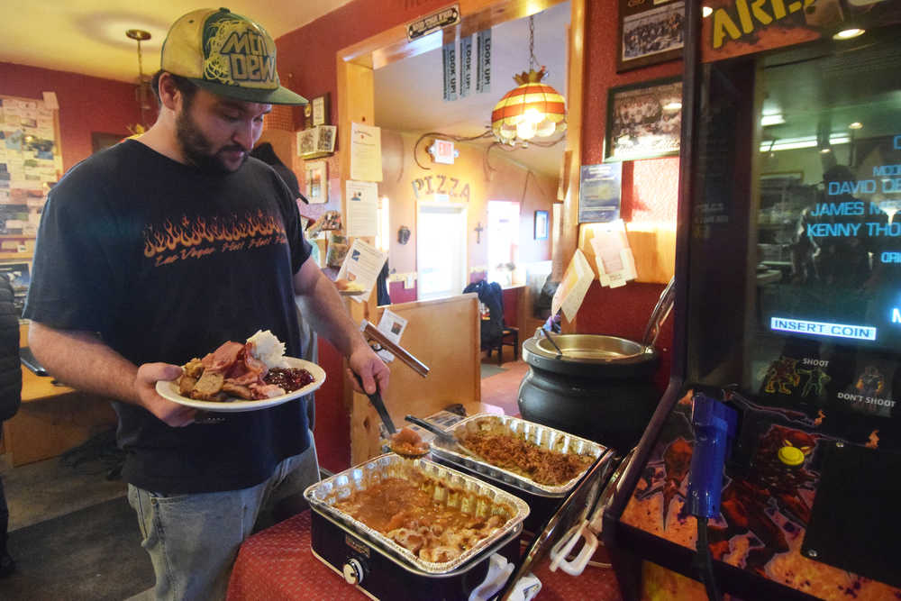 Photo by Megan Pacer/Peninsula Clarion Mahlon Troyer fills up his plate during the annual Thanksgiving meal put on at Charlie's Pizza on Thursday, Nov. 24, 2016 at the restaurant in Nikiski, Alaska. Set to close at the end of the year, the owners of Charlie's Pizza hope to continue providing Thanksgiving meals in the future on a smaller scale.