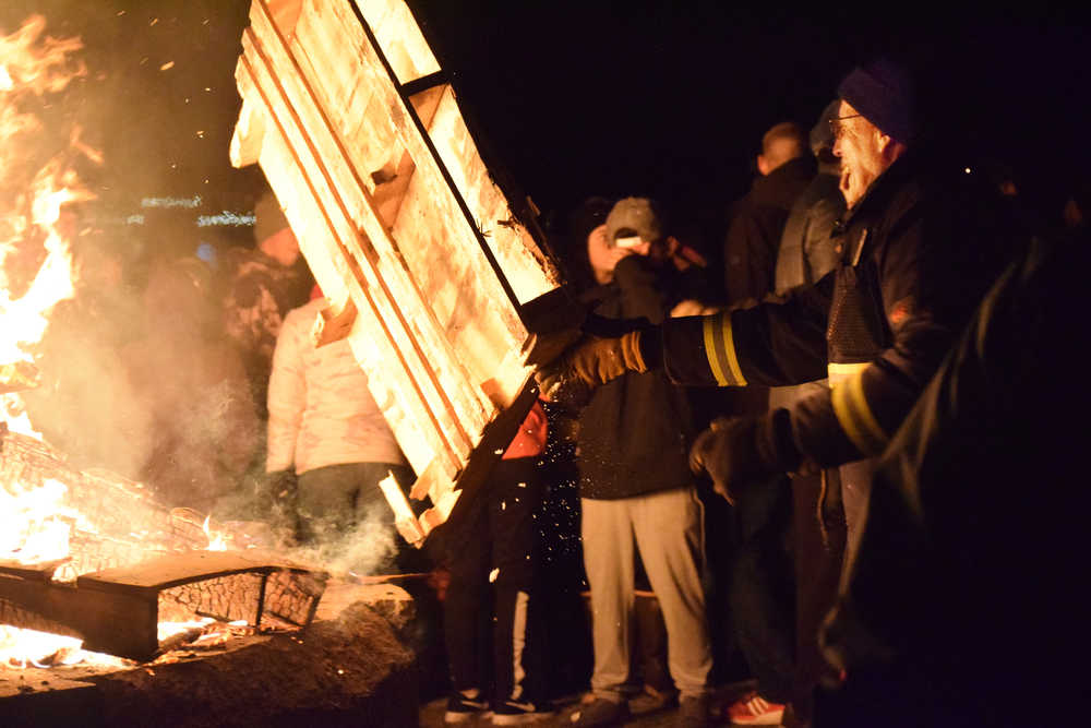 Photo by Megan Pacer/Peninsula Clarion Joe Harris tosses another pallet onto the bonfire during the annual Christmas Comes to Kenai celebration with the help of Raymond Hanson on Friday, Nov. 25, 2016 outside the Kenai Chamber of Commerce and Visitor Center in Kenai, Alaska.