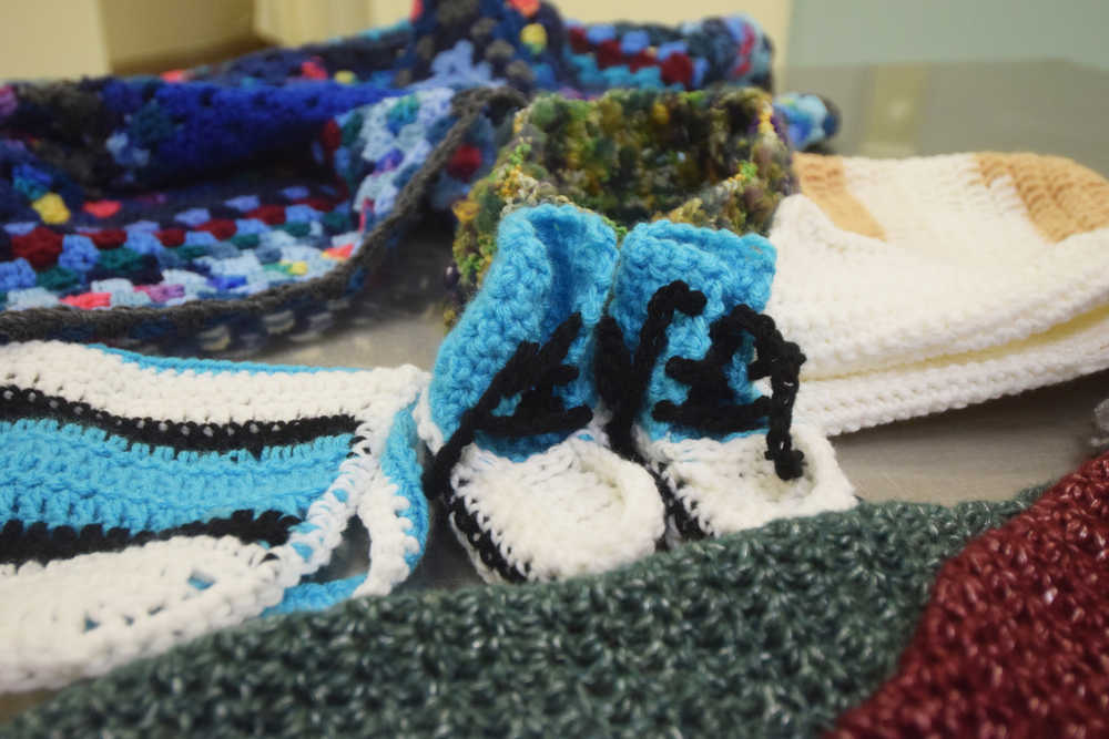 Photo by Megan Pacer/Peninsula Clarion Booties, scarves, hats and more cover a table during a meeting of the Wildwood Correctional Complex's crochet program Tuesday, Nov. 29, 2016 at the complex's pretrial building in Kenai, Alaska. The items made by inmates through the program are sent around the peninsula to be enjoyed.