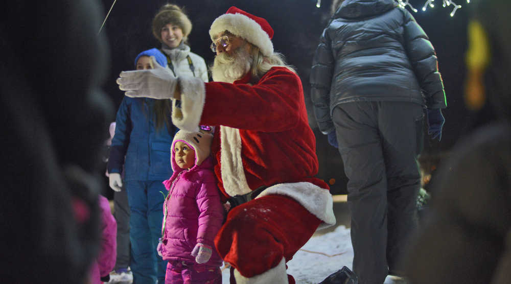 Photo by Ben Boettger/Peninsula Clarion Dave Caswell, portraying Santa Claus, poses with children during Soldotna's Christmas in the Park event on Saturday, Dec. 3 in Soldotna Creek Park. A crowd gathered in the park after sunset on Saturday to socialize around campfires, sing carols, light the park's artificial metal Christmas tree, and watch the Christmas film "The Polar Express."