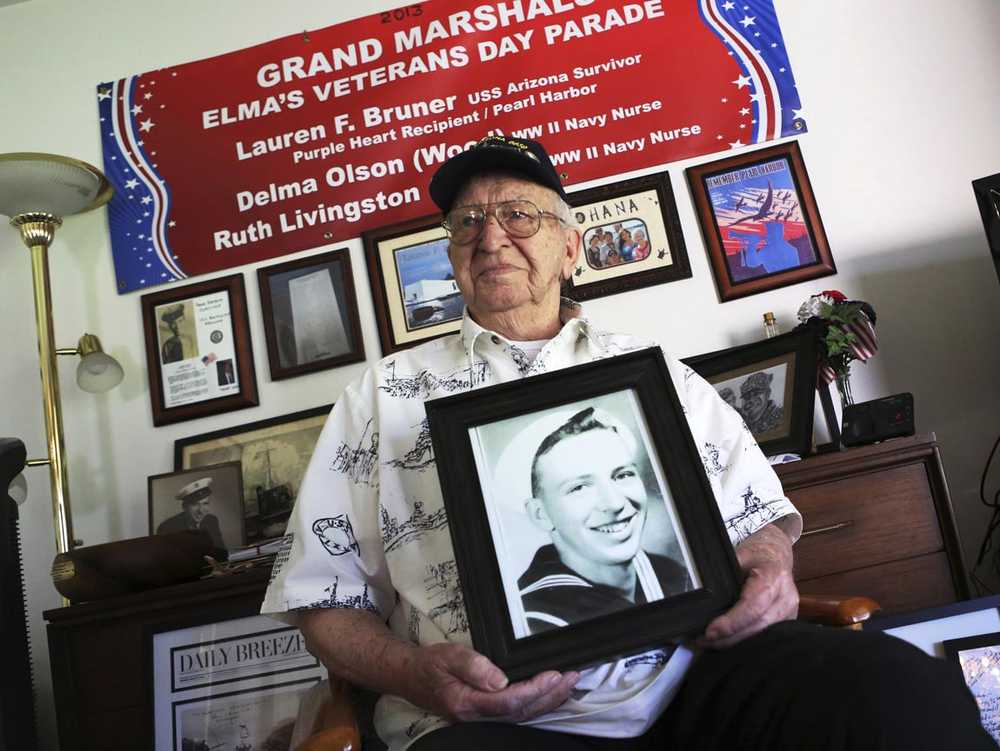 ADVANCE FOR USE MONDAY, DEC. 5, 2016 AND THEREAFTER-In this Thursday, Nov. 17, 2016 photo, Lauren Bruner, one of five remaining survivors of the USS Arizona which was attacked on Dec. 7, 1941, holds with a 1940 photo of himself, at his home in La Mirada, Calif. Bruner was getting ready for church when the alarm on his battleship sounded. (AP Photo/Reed Saxon)