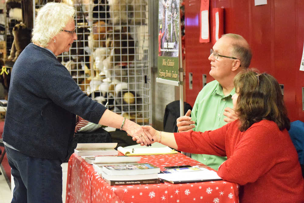 Photo by Megan Pacer/Peninsula Clarion Mike Chihuly and his wife, Shirley, greet a passerby while he signs copies of his recently published book, "Alaska Fish and Fire," on Saturday, Nov. 26, 2016 at the annual Peninsula Art Guild's Fine Arts and Crafts Fair in Kenai, Alaska.