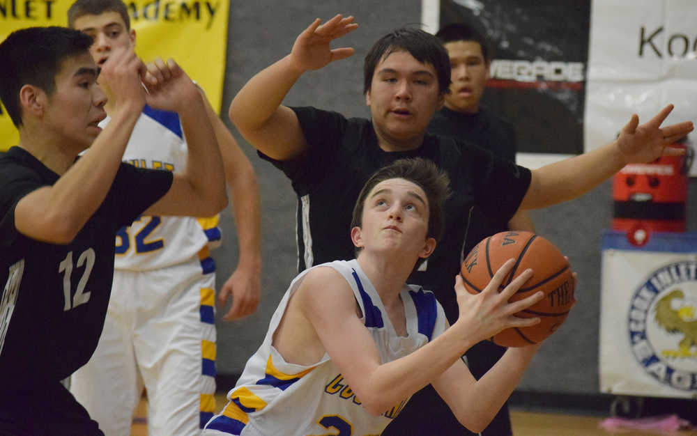 Photo by Joey Klecka/Peninsula Clarion Cook Inlet Academy freshman Robert Walsh looks to the rim against a wall of Kodiak ESSS guards, Thursday night at CIA.