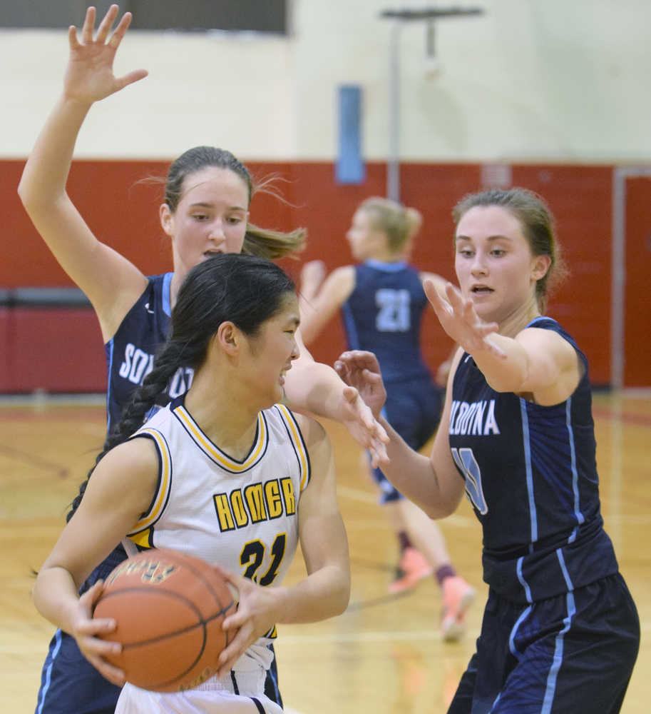 Photo by Jeff Helminiak/Peninsula Clarion Homer's Kailee Veldstra tries to get out of the trap set by Soldotna's Danica Schmidt and Aliann Schmidt on Friday at Kenai Central High School.