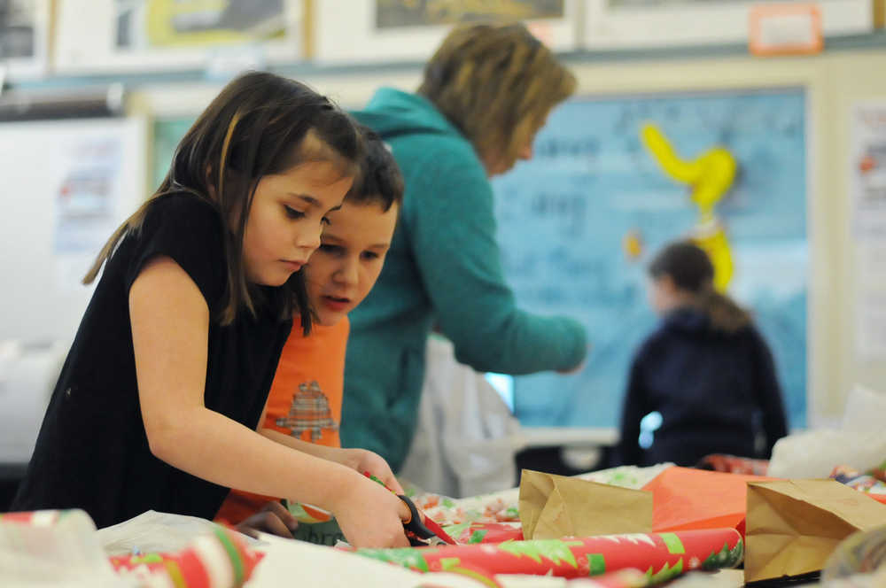 Photo by Elizabeth Earl/Peninsula Clarion Kylie Villa (left), a second-grader at Soldotna Elementary School, cuts wrapping paper with the help of Dylan Hammerle (right) to wrap the gifts she purchased in the holiday gift shop put on by the school's Parent-Teacher Organization in the library on Wednesday, Dec. 14, 2016 in Soldotna, Alaska.